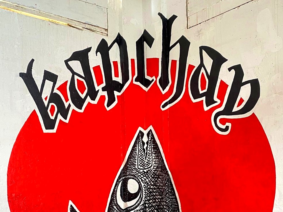 The corner Kapchay mural — a fish beneath a red sun